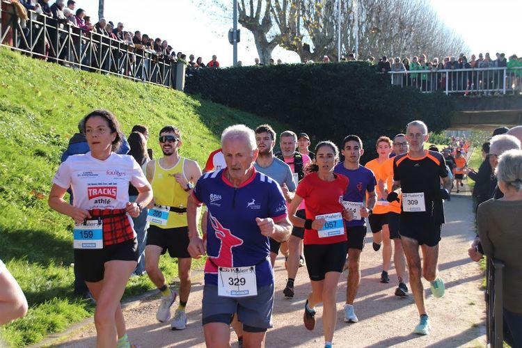 Des coureurs le long des berges du Gers et des spectateurs qui les applaudissent en haut du pont